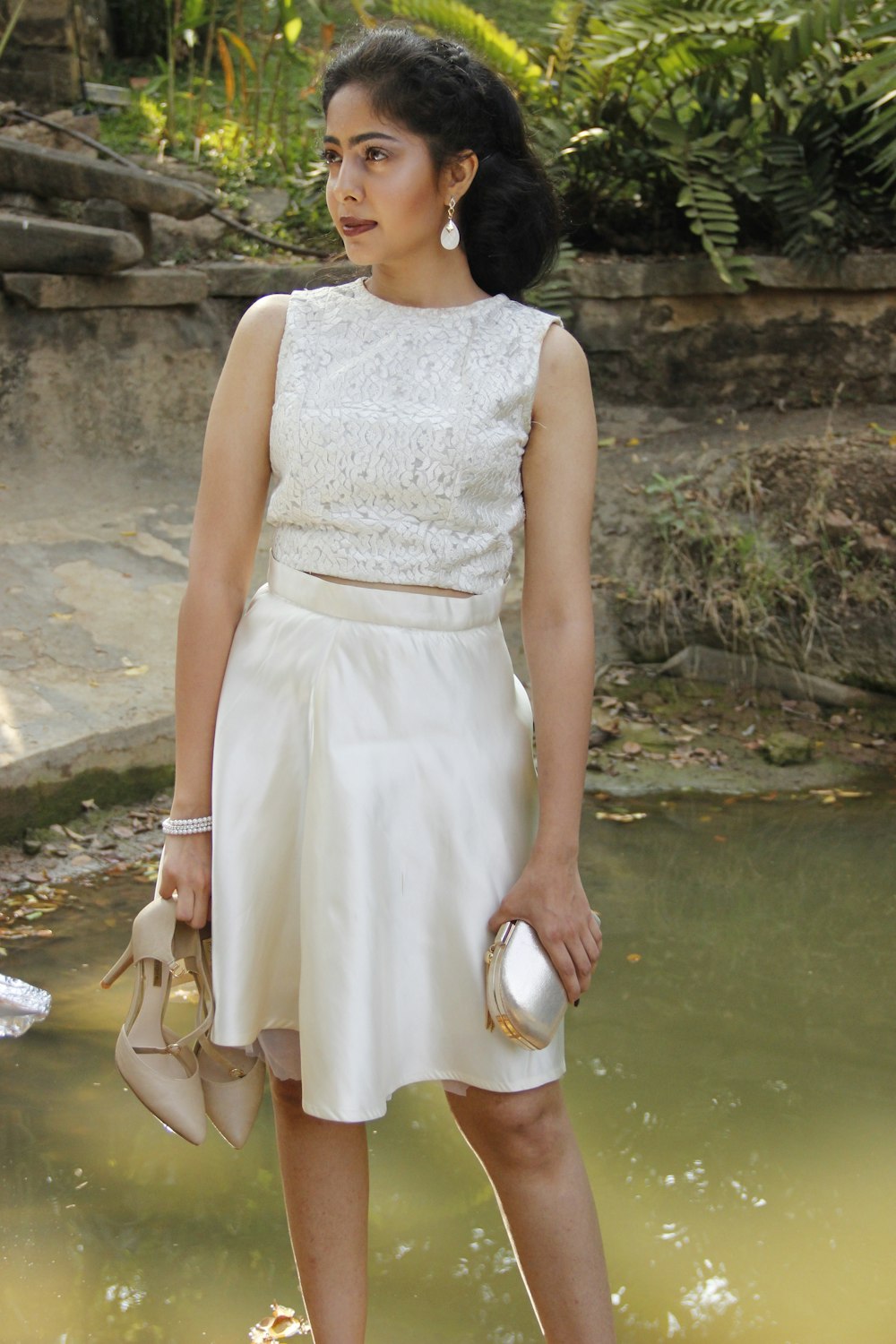 a woman in a white dress standing in front of a pond
