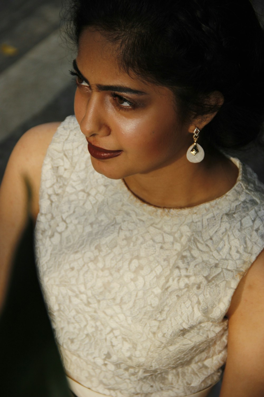a woman wearing a white dress and a pair of earrings