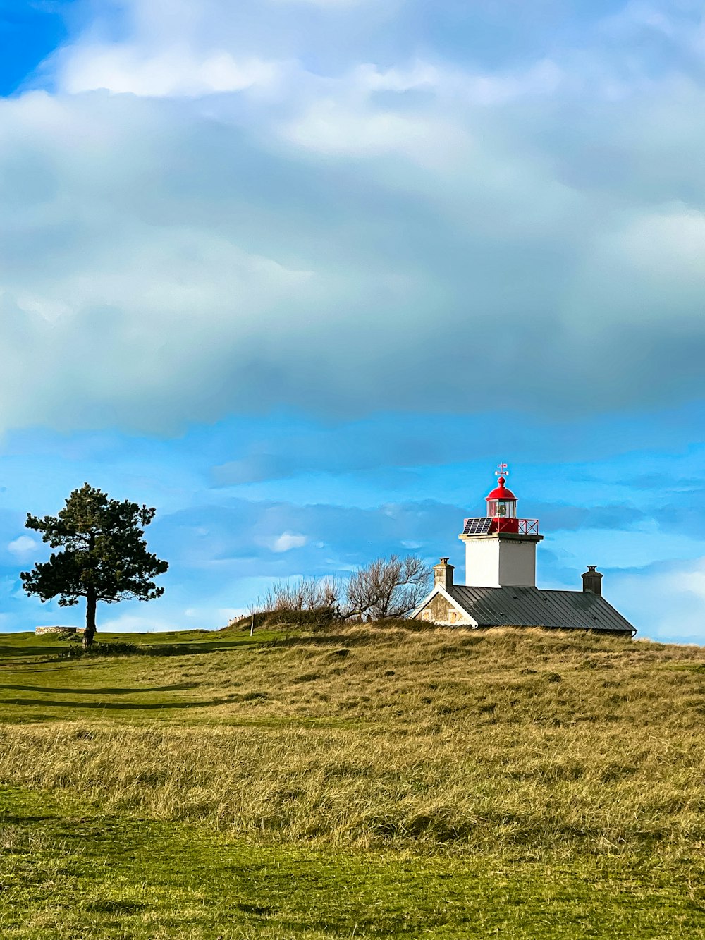 a lighthouse on top of a grassy hill