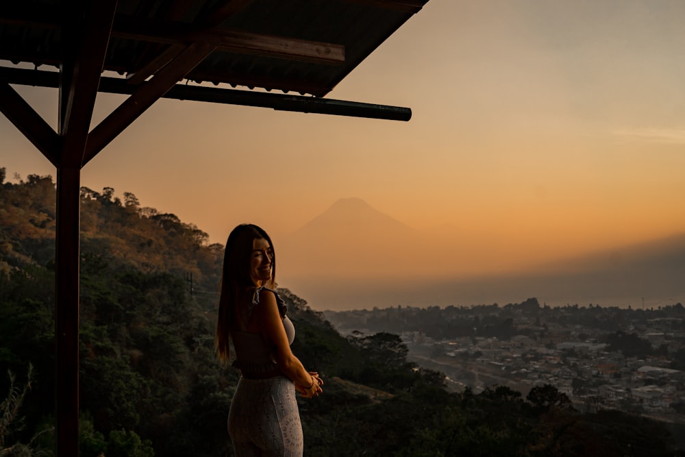 a woman standing on top of a lush green hillside