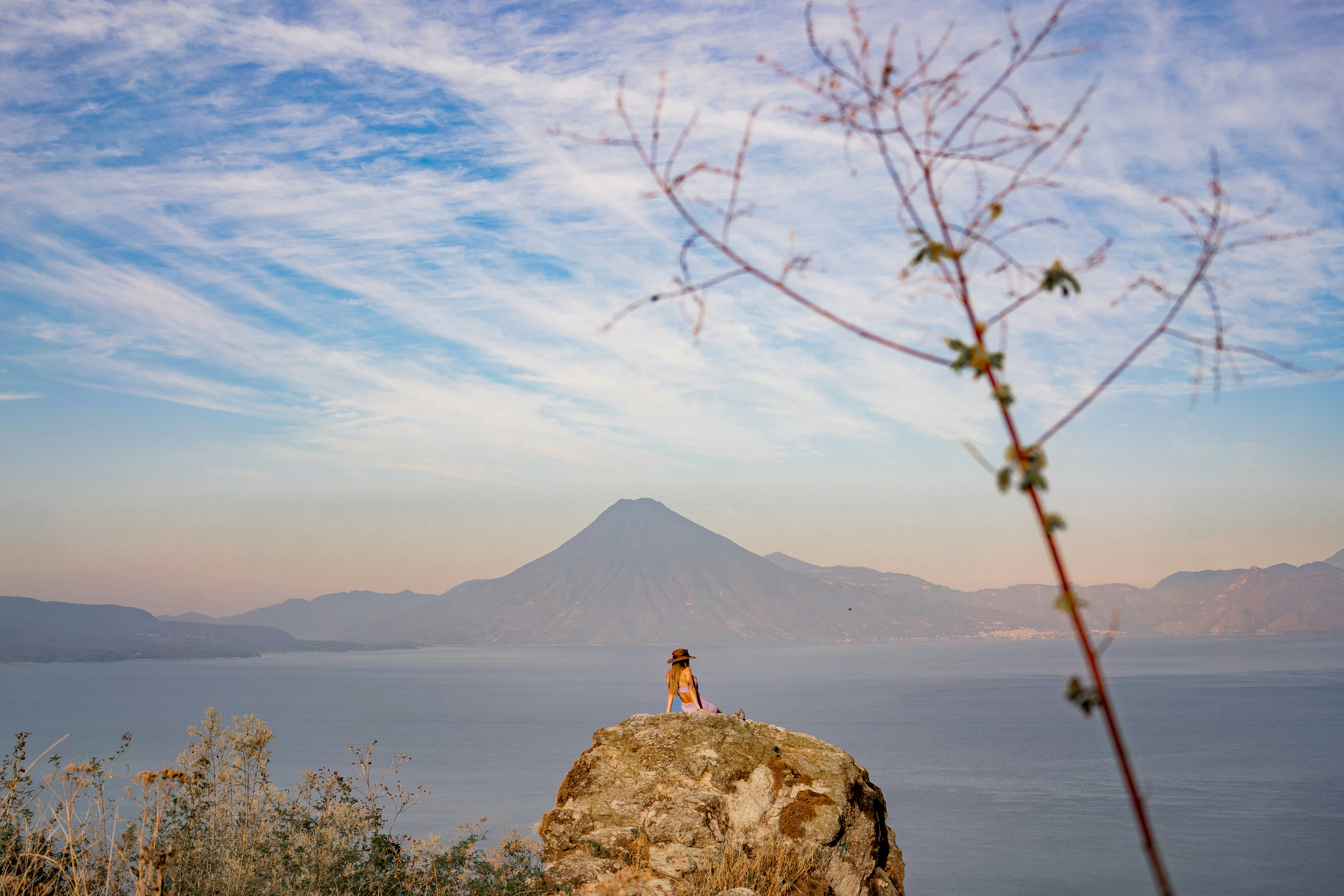 a person sitting on a rock overlooking a body of water, 