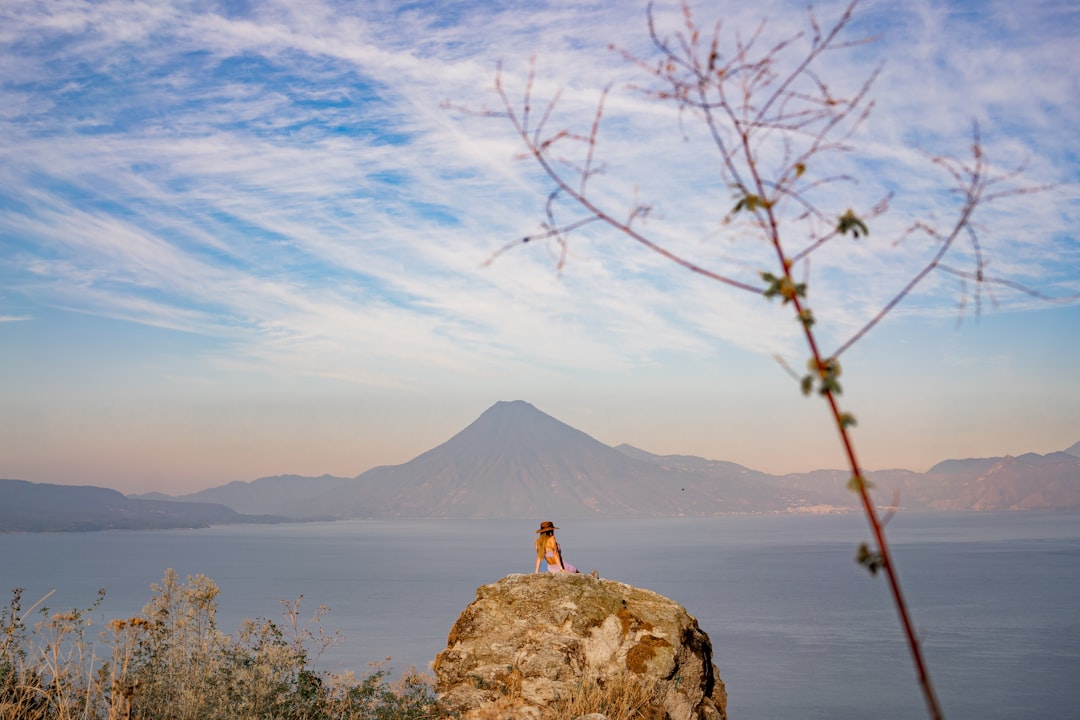 a person sitting on a rock overlooking a body of water,