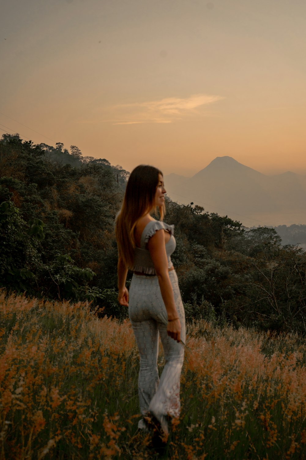 a woman standing in a field at sunset