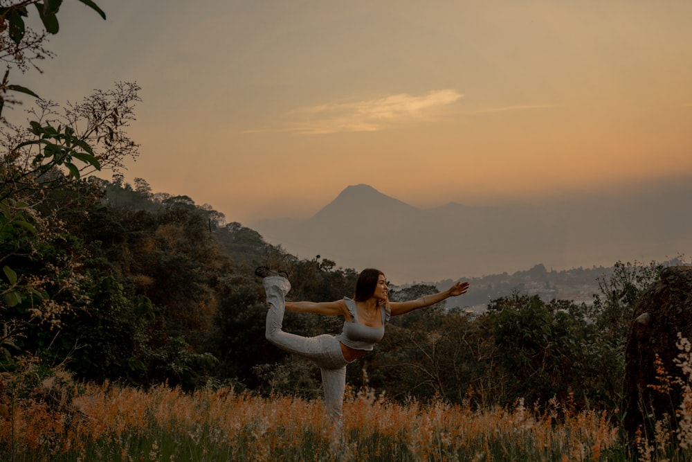 uma mulher fazendo uma pose de ioga em um campo