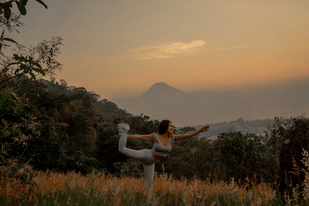 a woman doing a yoga pose in a field