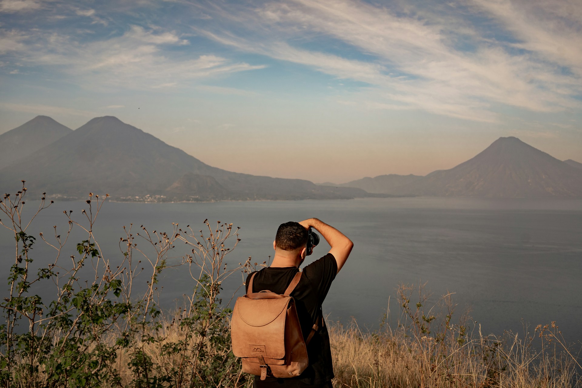 a man standing on top of a hill next to a body of water