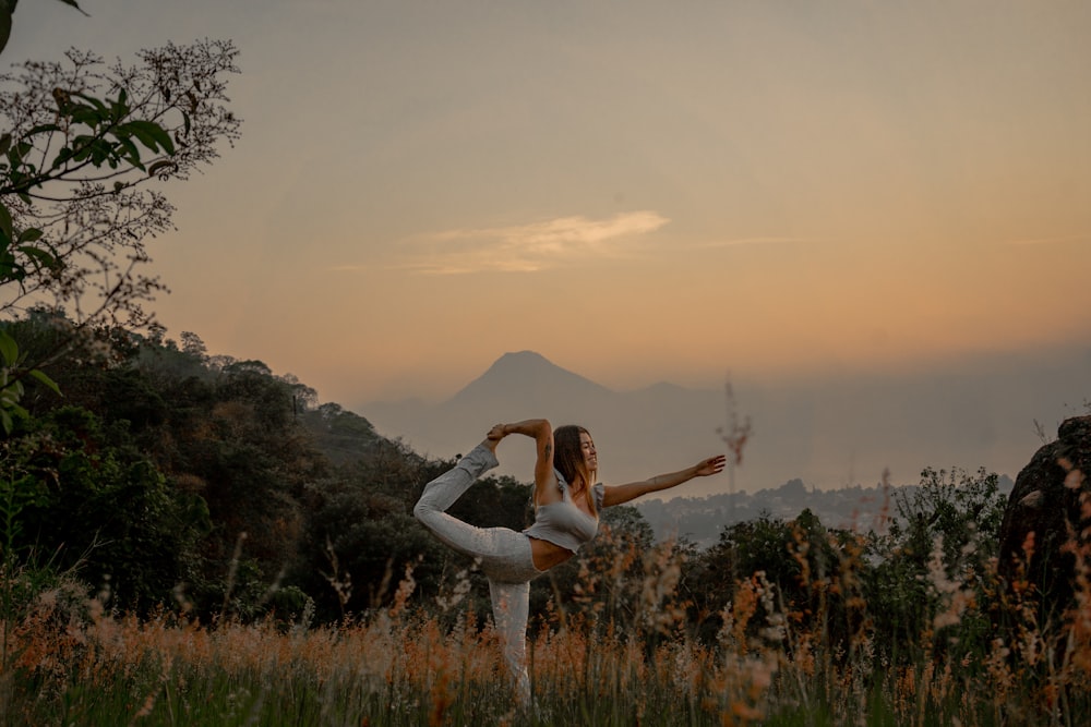 a woman doing a yoga pose in a field