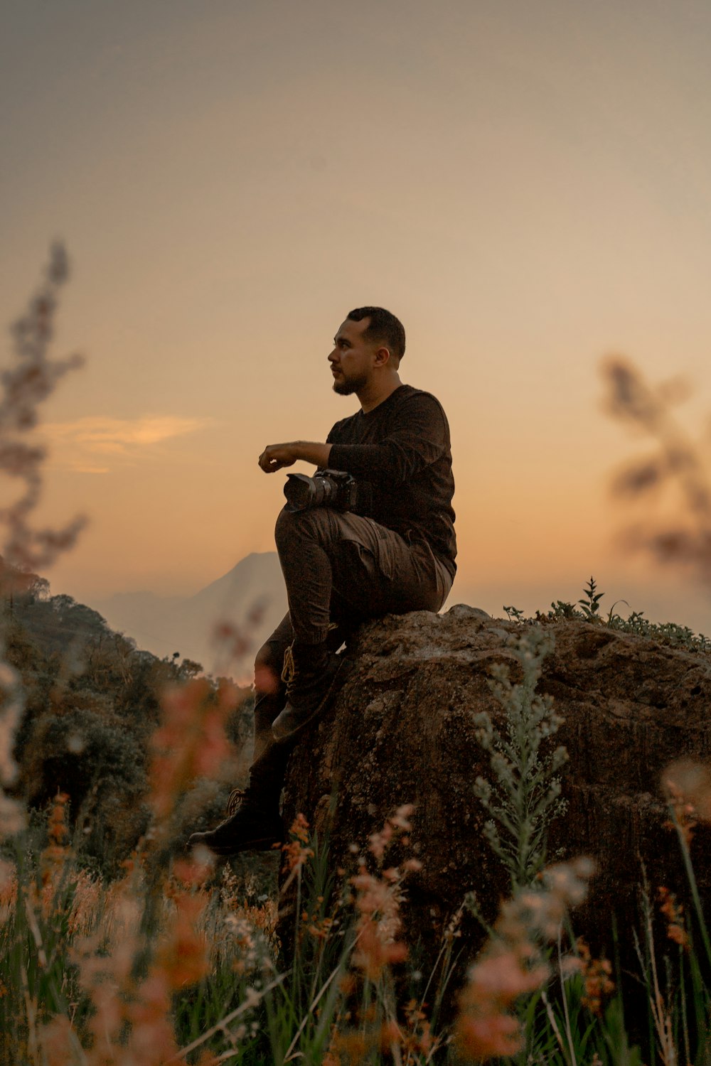 a man sitting on top of a large rock