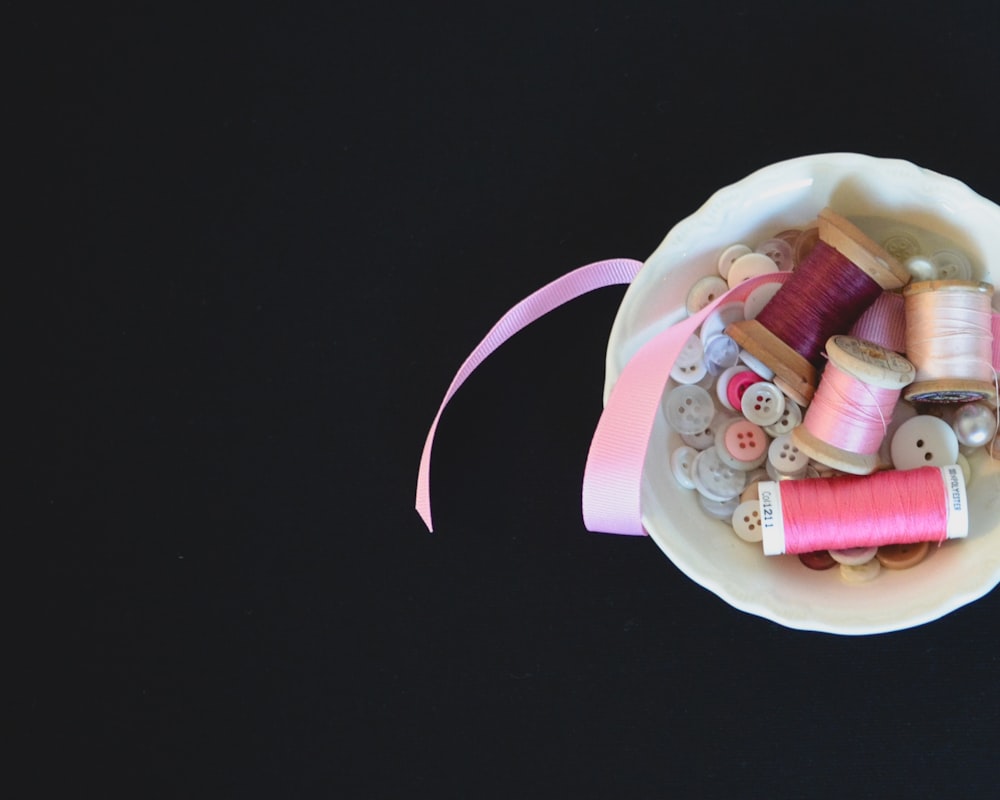 a white bowl filled with lots of spools of thread