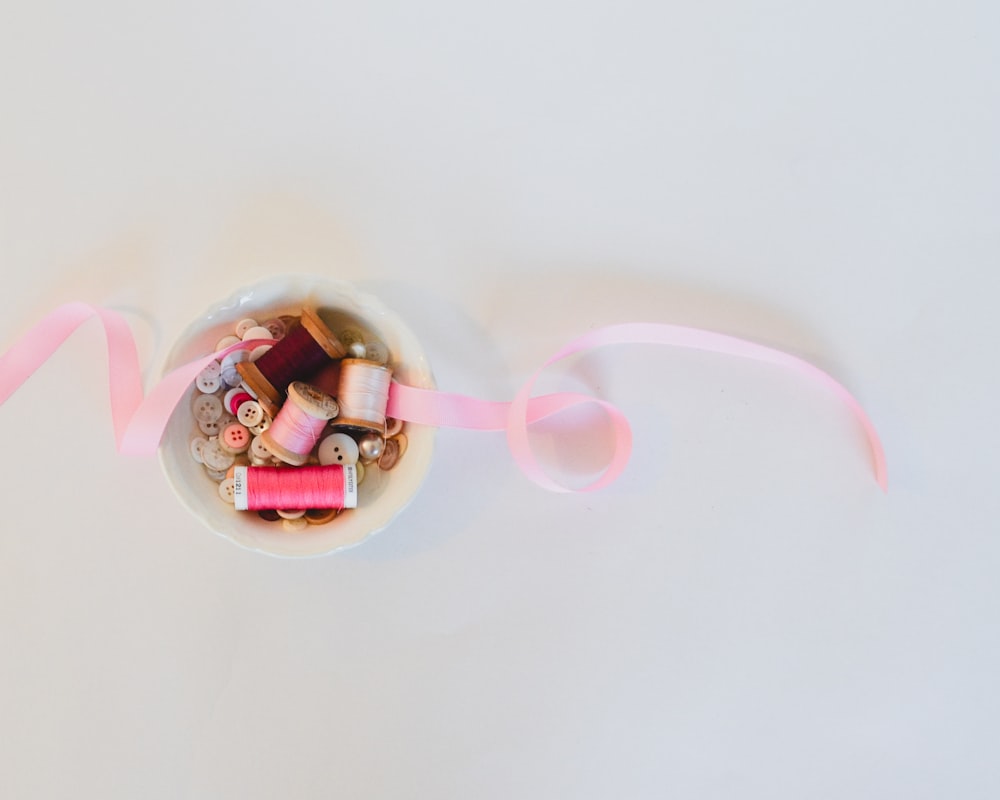 a bowl filled with candy and a pink ribbon