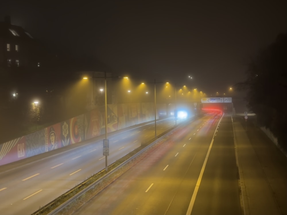 a foggy night on a highway with cars driving down it