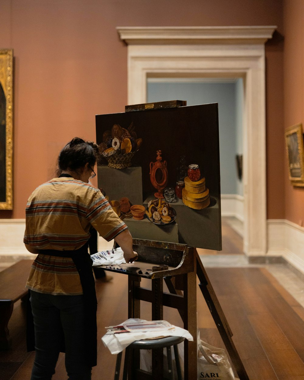 a woman standing in front of a painting on a easel