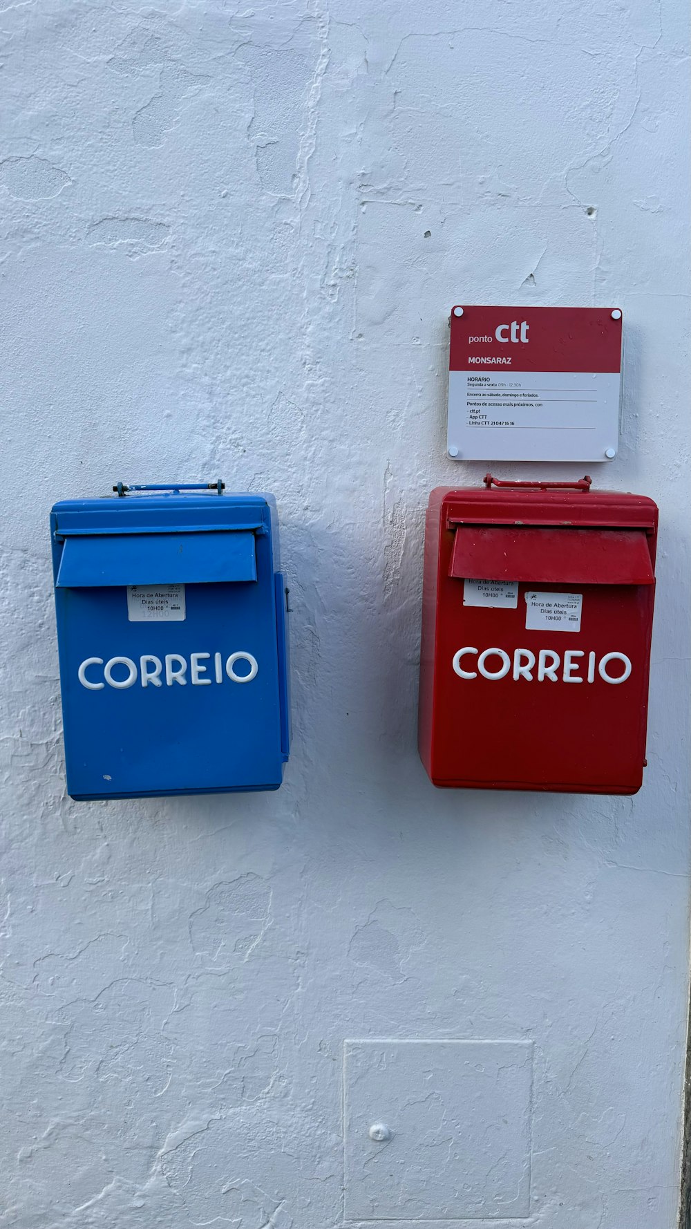 ein paar rote und blaue Briefkästen an einer weißen Wand