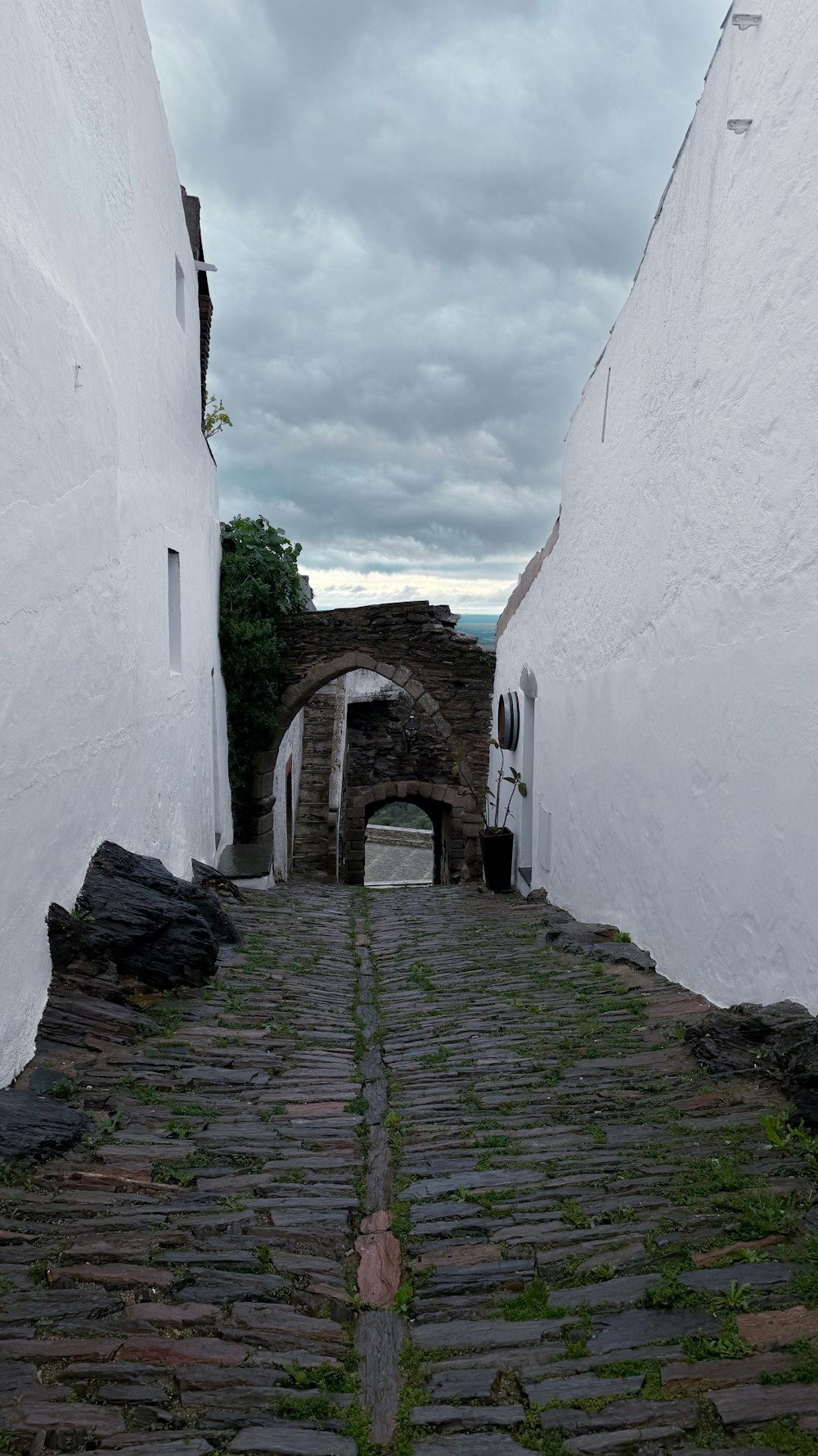 a cobblestone street with a stone arch between two buildings