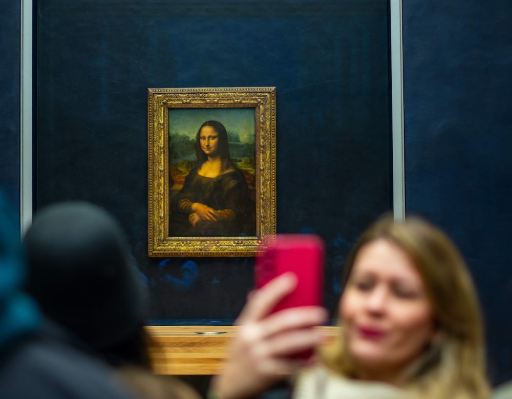 a woman taking a picture of a painting