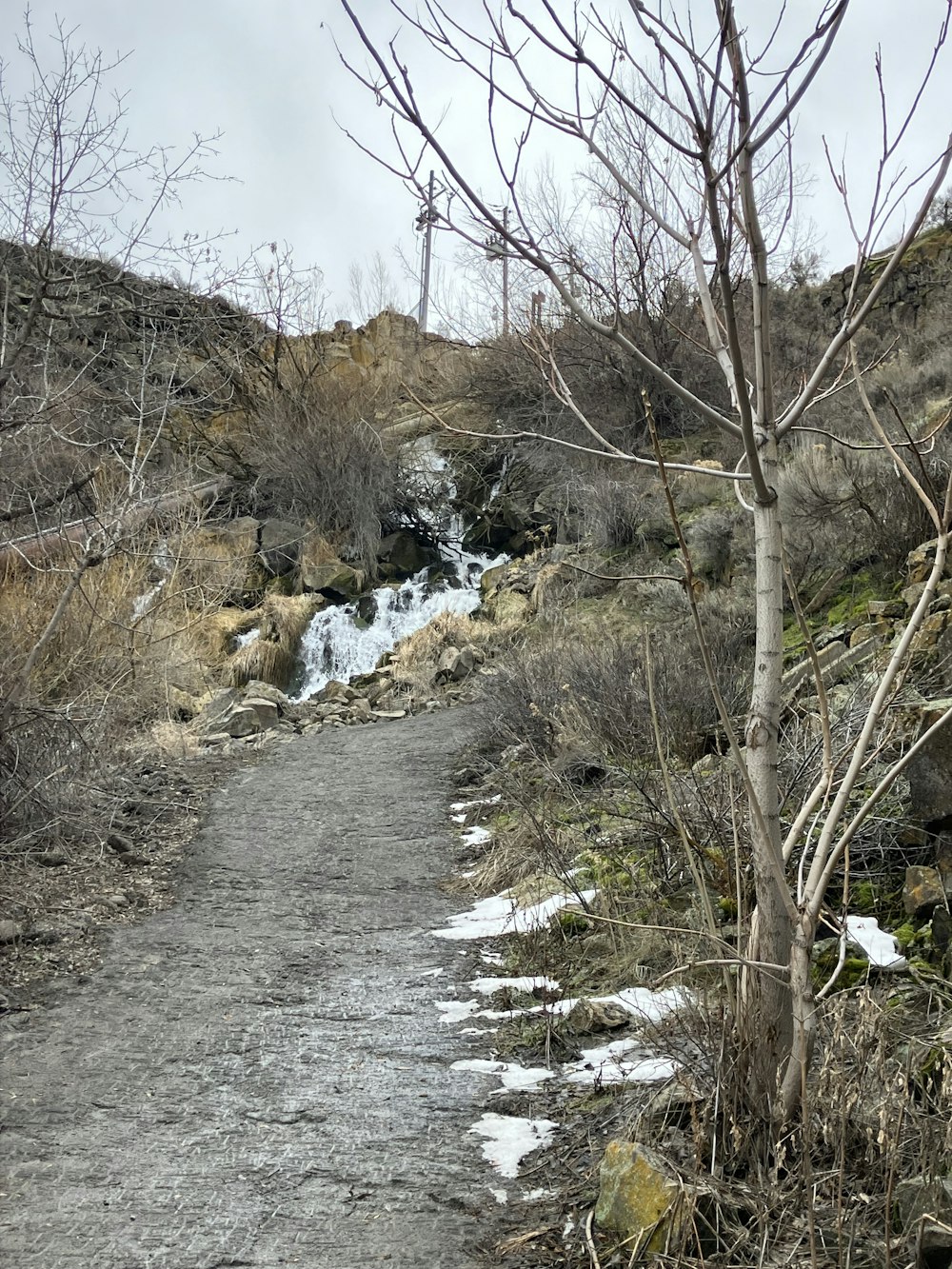 a dirt road with a waterfall in the background