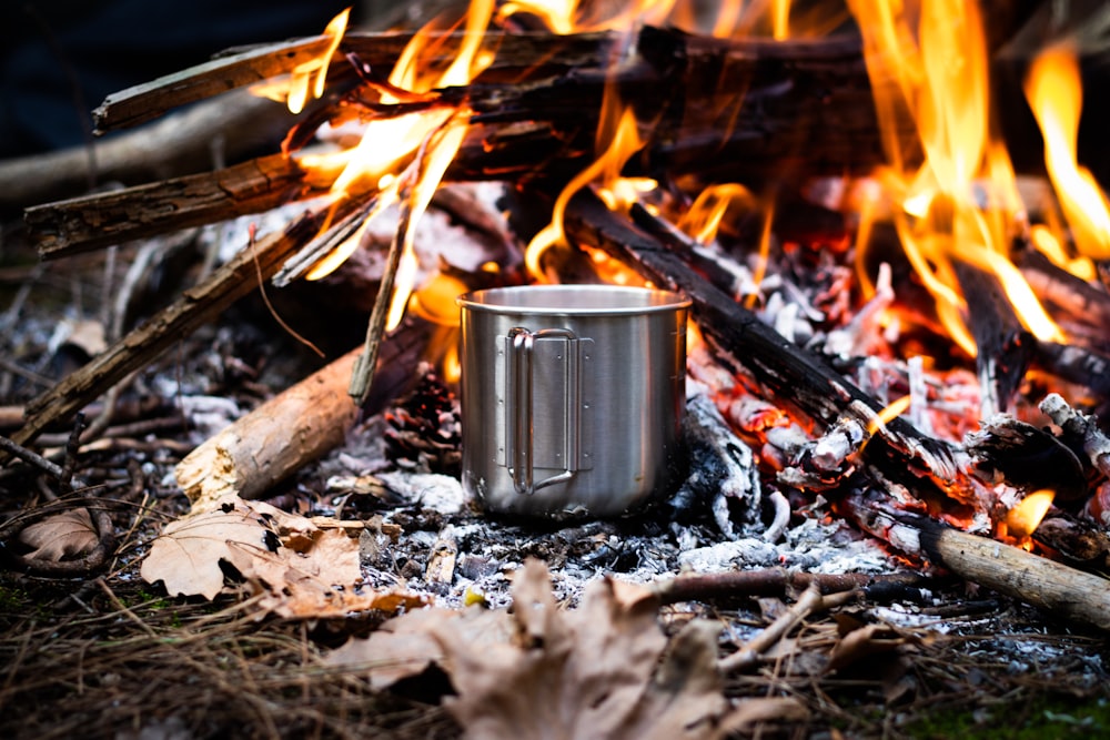 a campfire with a cup of coffee sitting in front of it