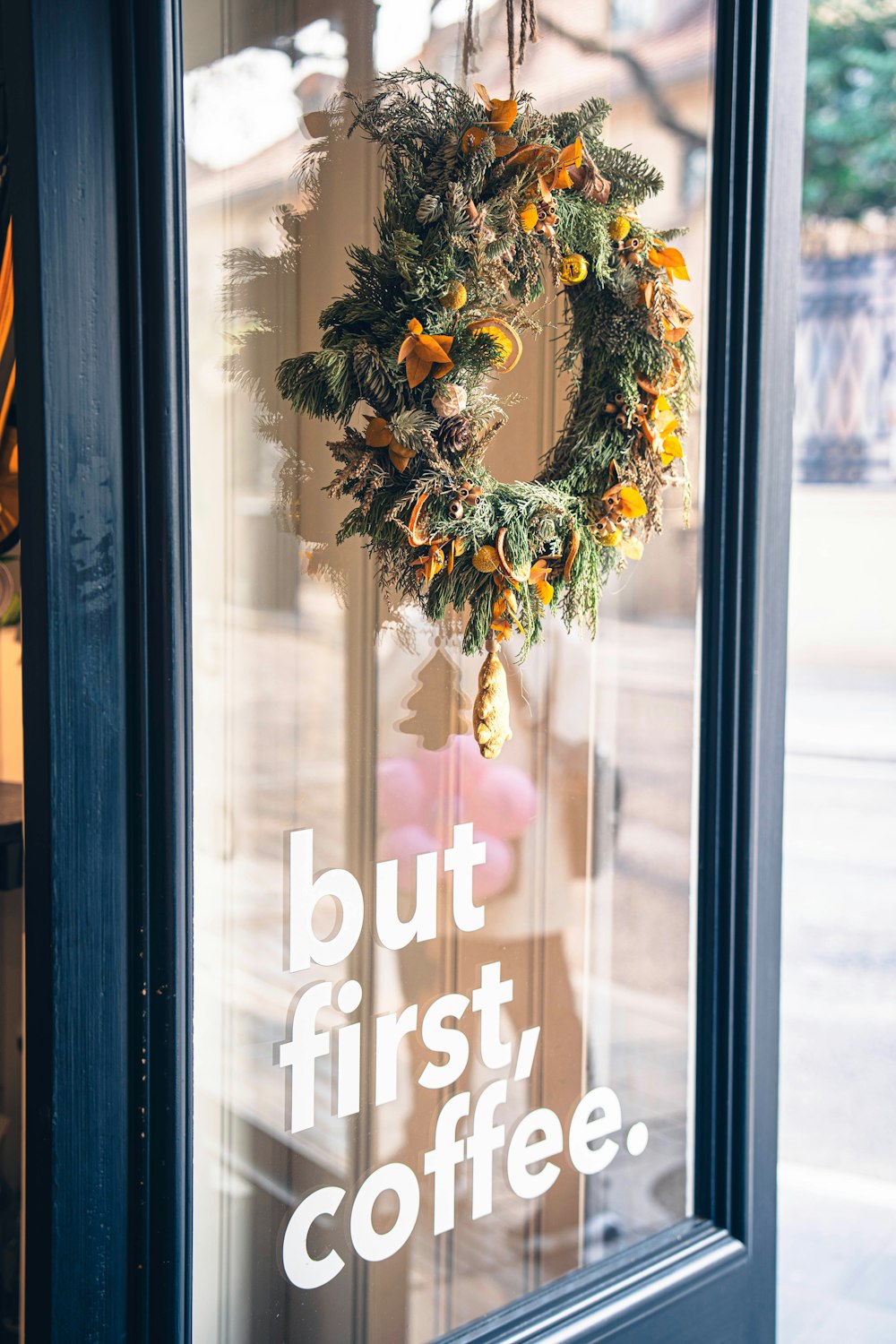 a wreath hanging on the front door of a coffee shop