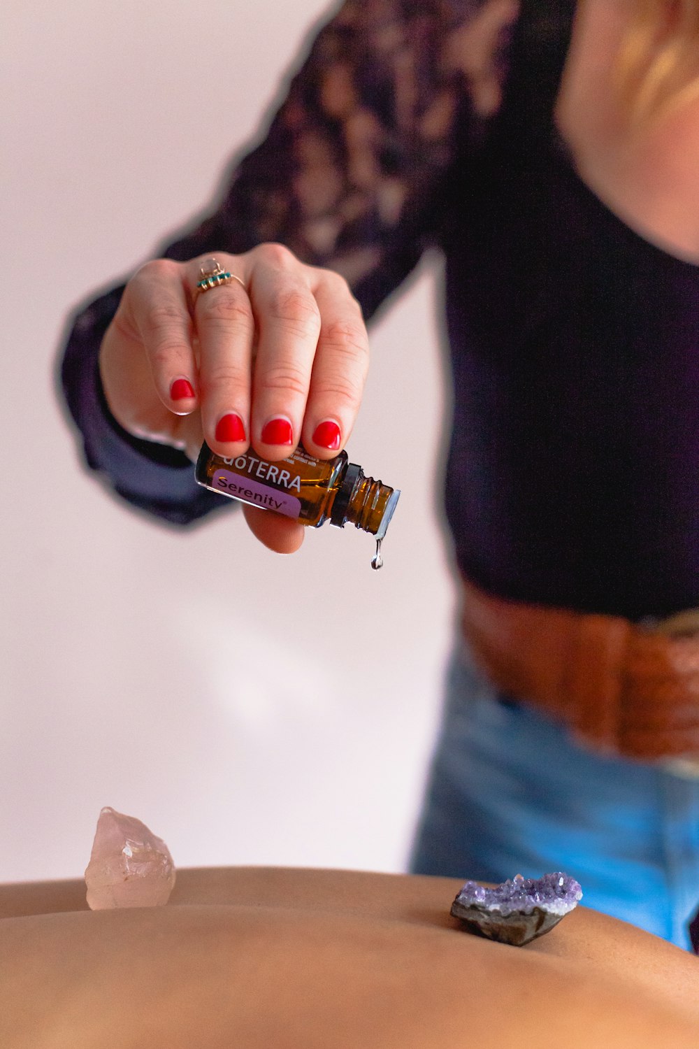 a woman getting a back massage with a bottle of essential oils