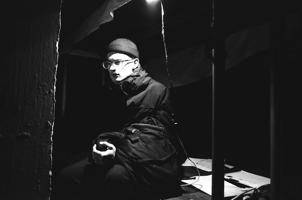 uma foto em preto e branco de um homem sentado no escuro