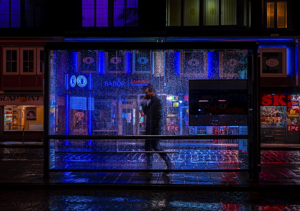 a man walking down a rain soaked street at night