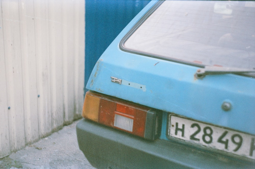 a blue car parked next to a white wall