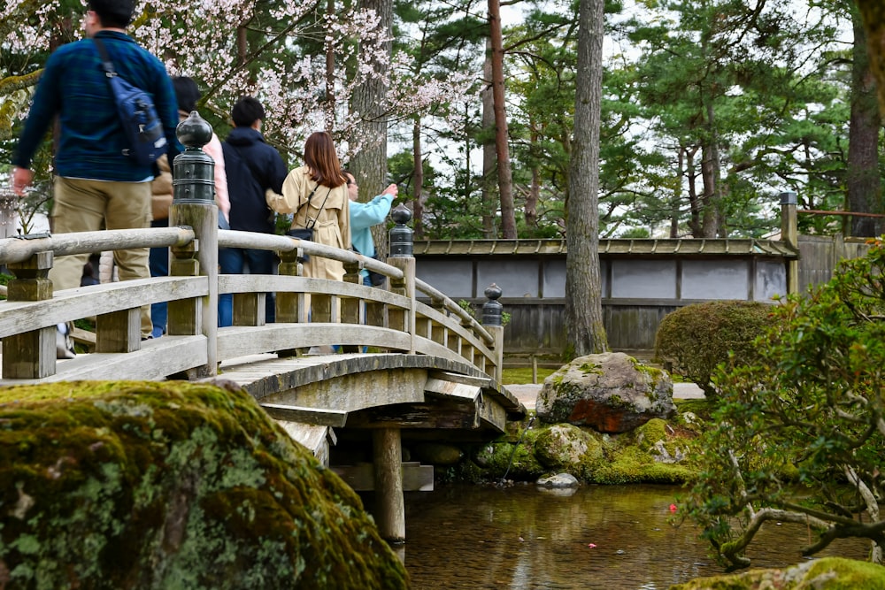 a group of people standing on a bridge over a stream