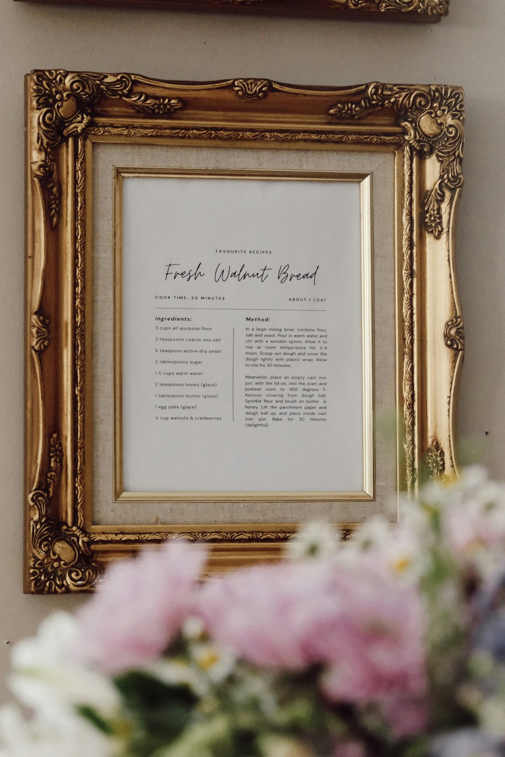 a gold framed picture hanging on a wall next to a vase of flowers