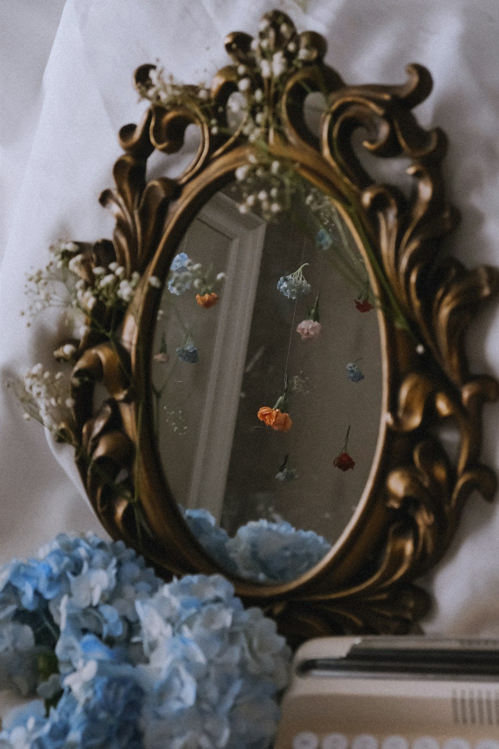 um espelho sentado em cima de uma cama ao lado de flores azuis