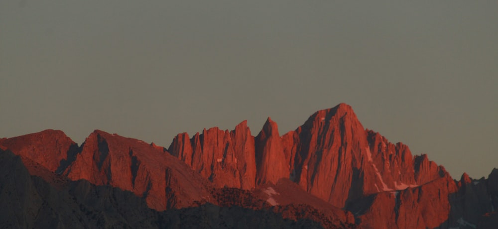 a red mountain range with a dark sky in the background