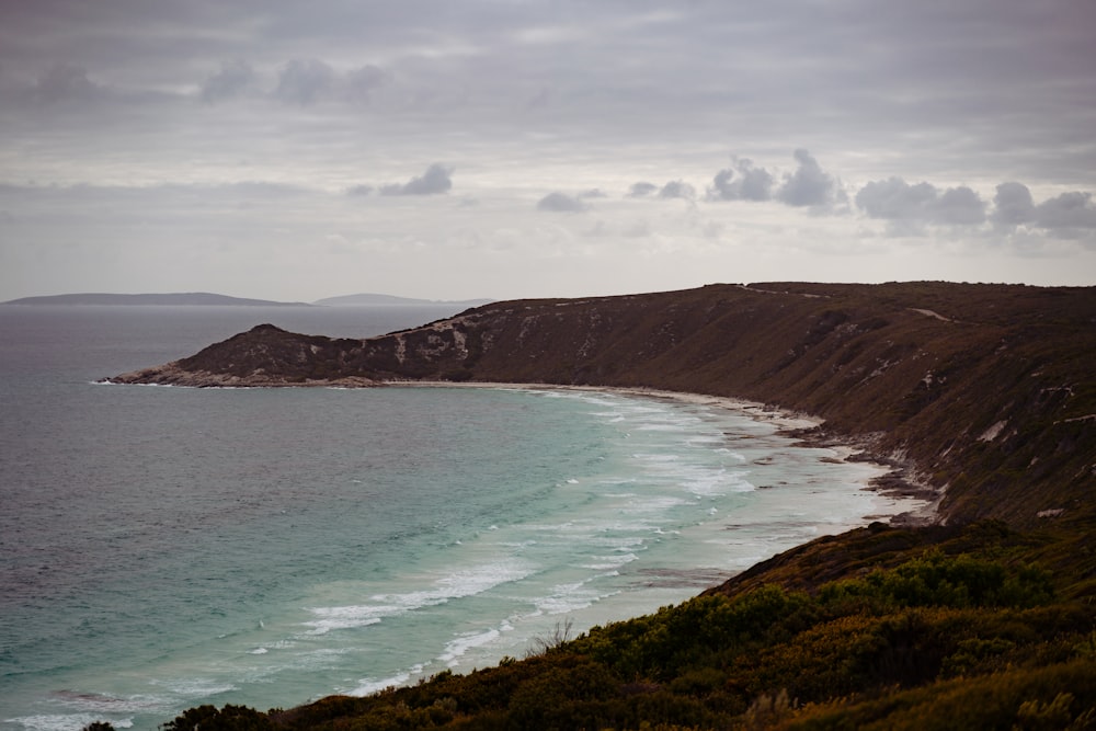 a large body of water sitting next to a lush green hillside