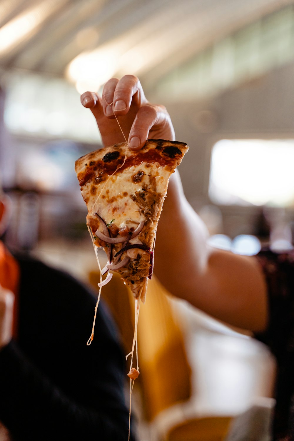 a person holding a slice of pizza in their hand