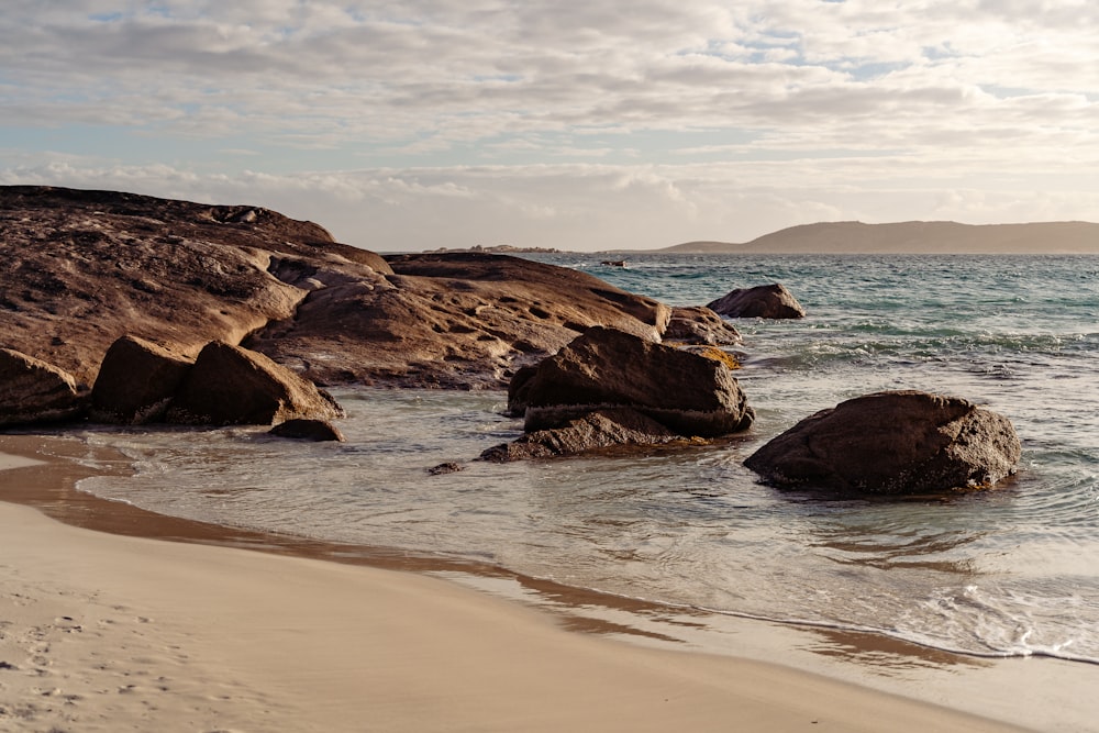 a sandy beach with rocks in the water