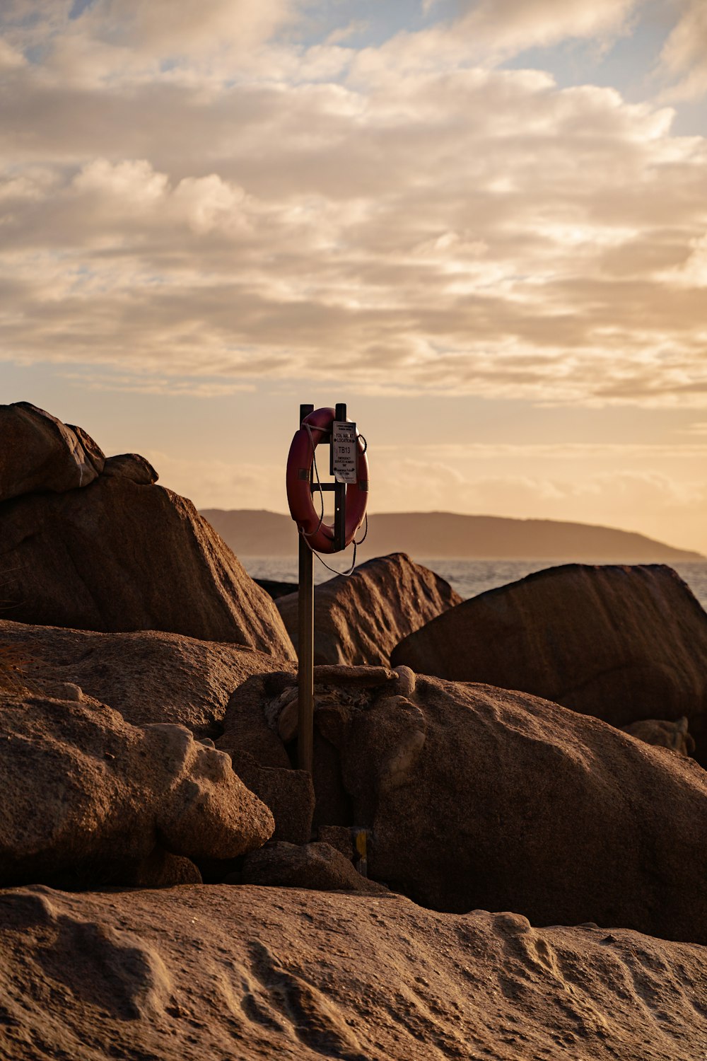 a red and white sign sitting on top of a rocky beach