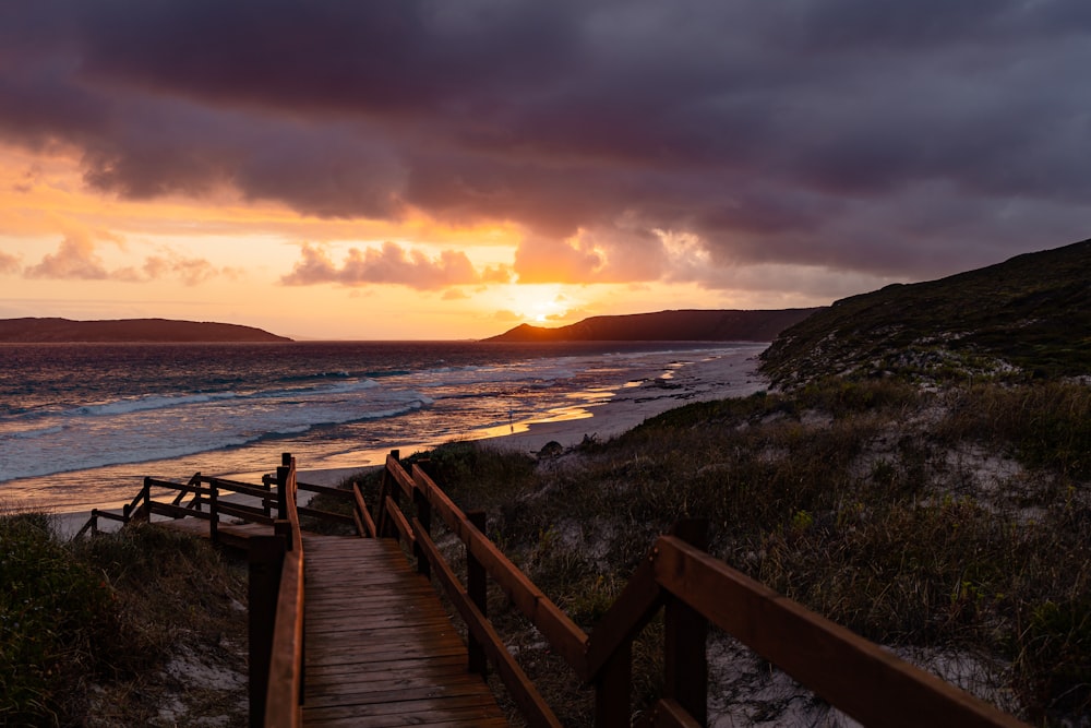 a wooden staircase leading to the beach at sunset