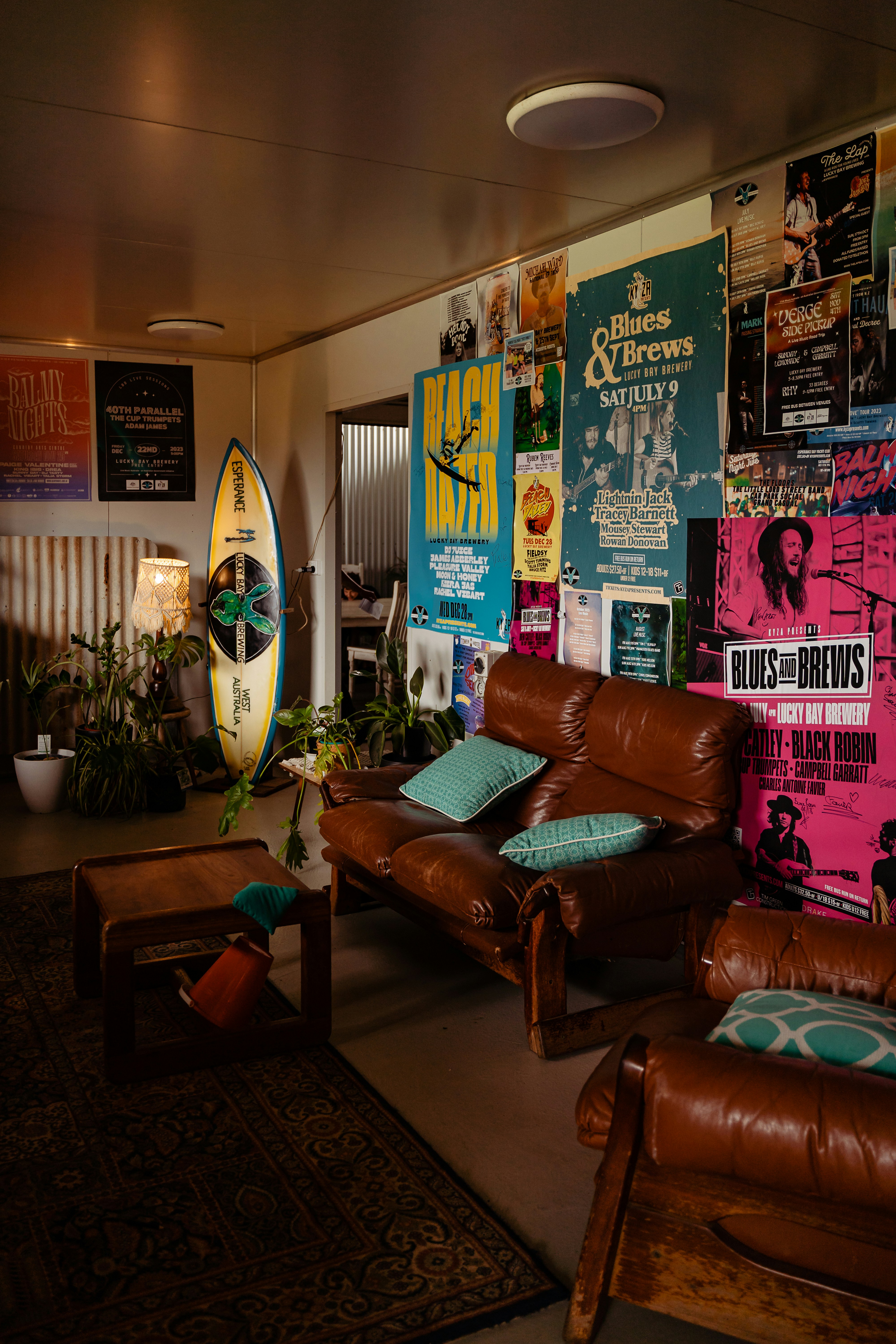 a living room filled with furniture and a surfboard on the wall