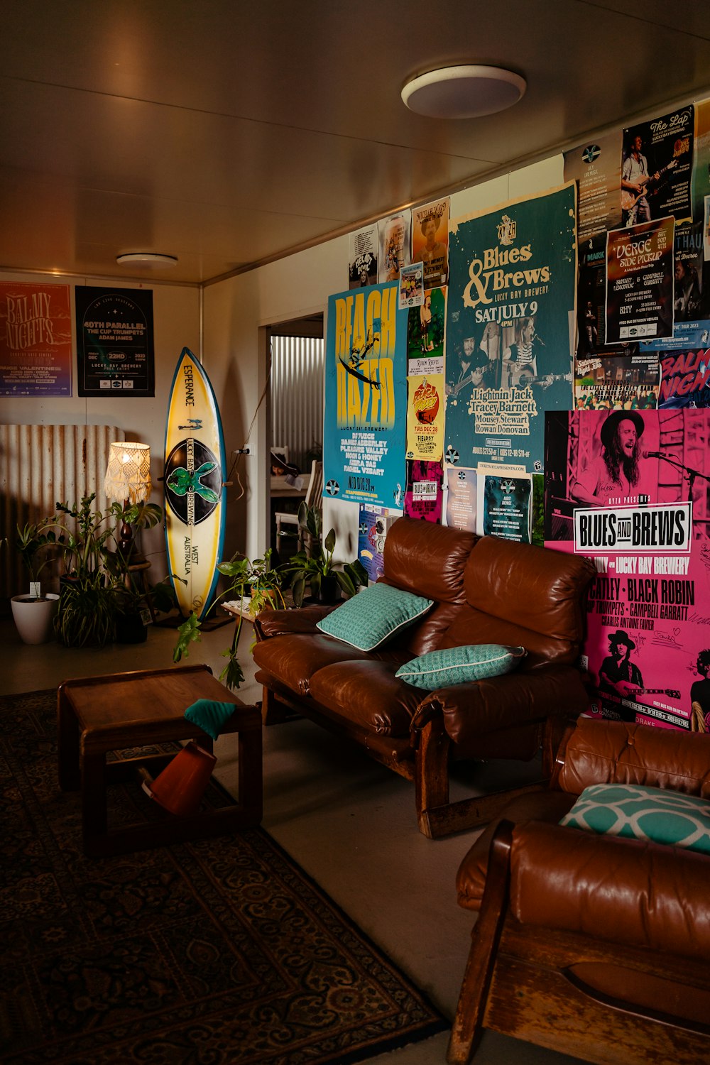 a living room filled with furniture and a surfboard on the wall