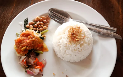 Plate of Balinese nasi campur mixed rice with shredded chicken and side dishes