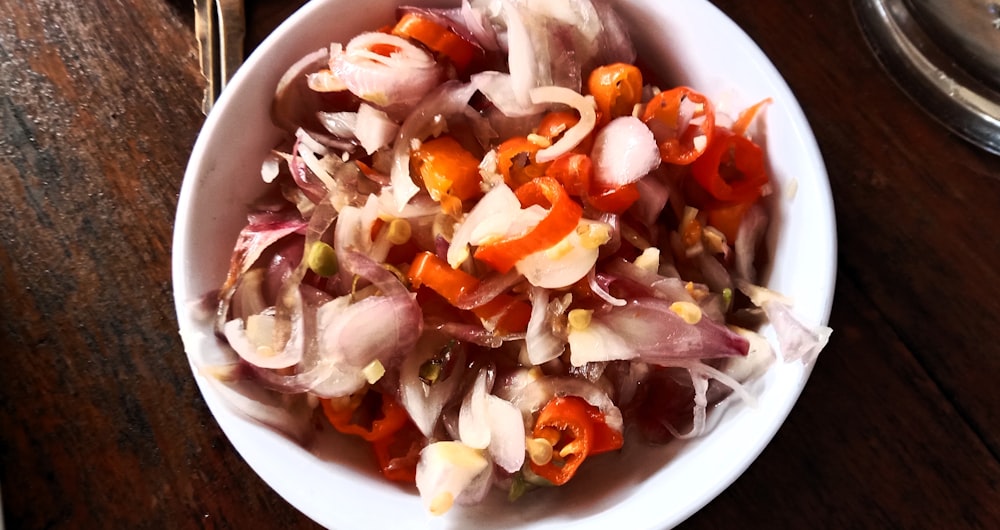 a white bowl filled with chopped vegetables on top of a wooden table