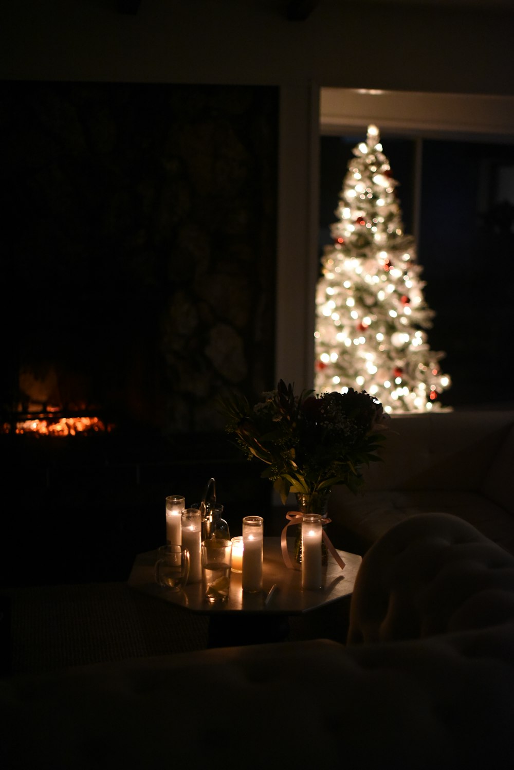 a living room with a christmas tree and lit candles
