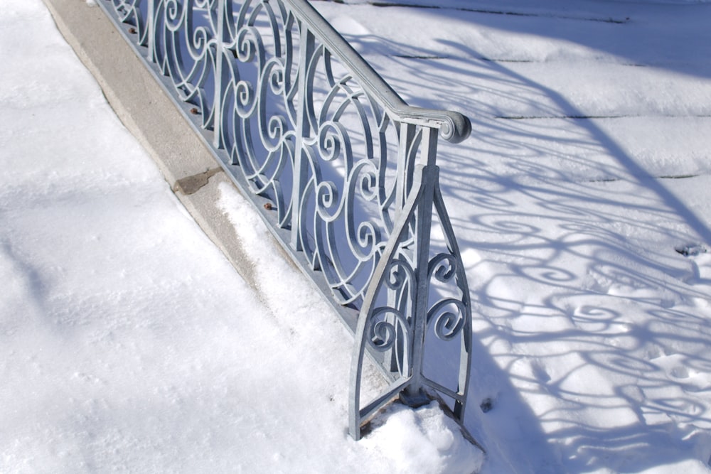 a metal bench sitting on top of snow covered ground