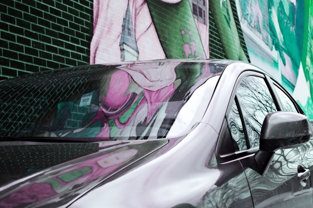 a car parked in front of a wall with graffiti