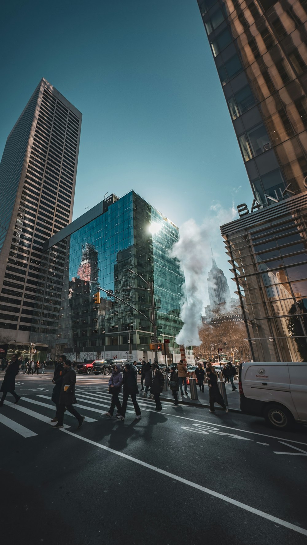 a group of people walking across a street next to tall buildings