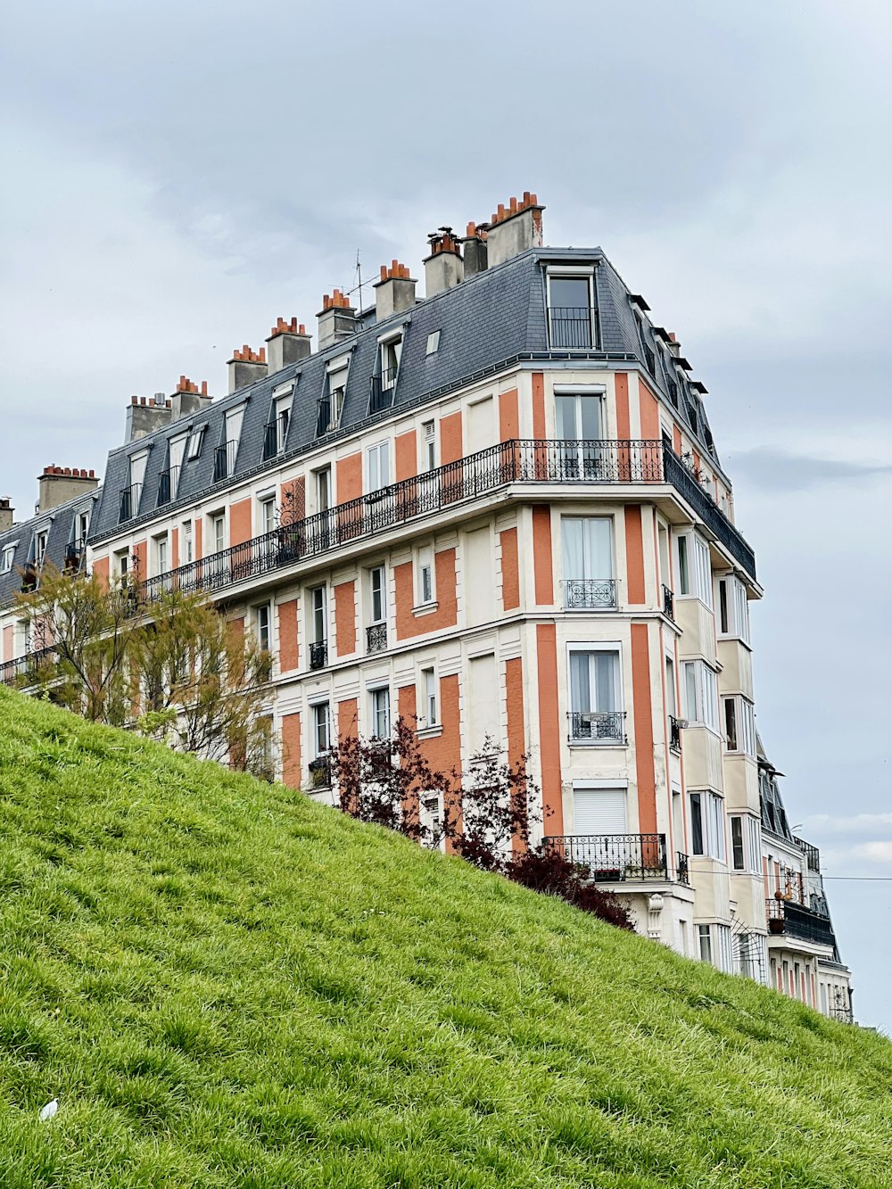 a very tall building sitting on top of a lush green hillside