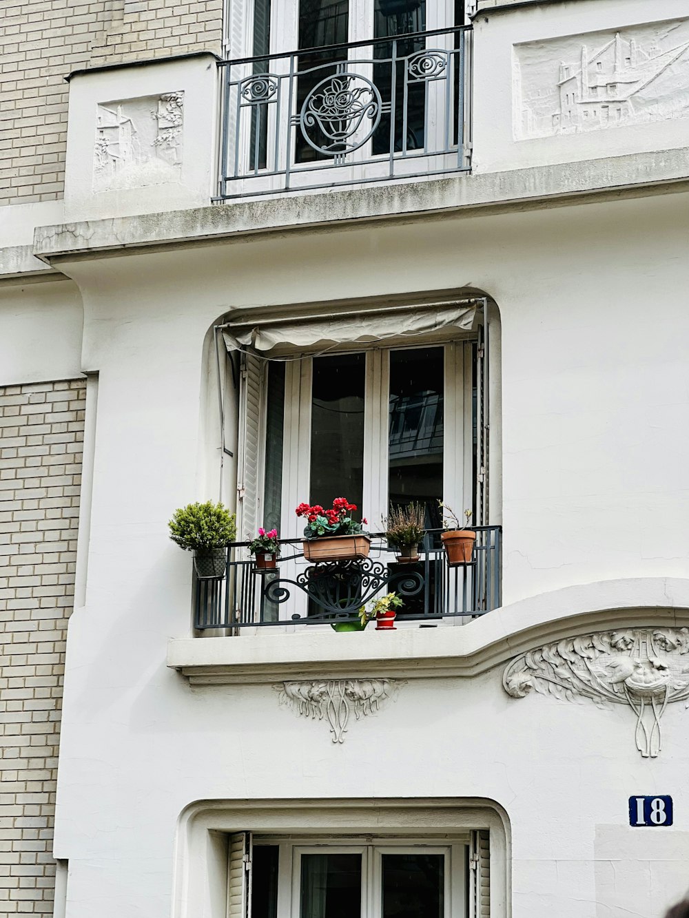 a white building with a balcony with flowers on it