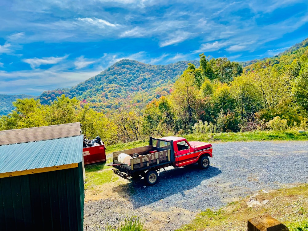 a red truck parked in front of a barn