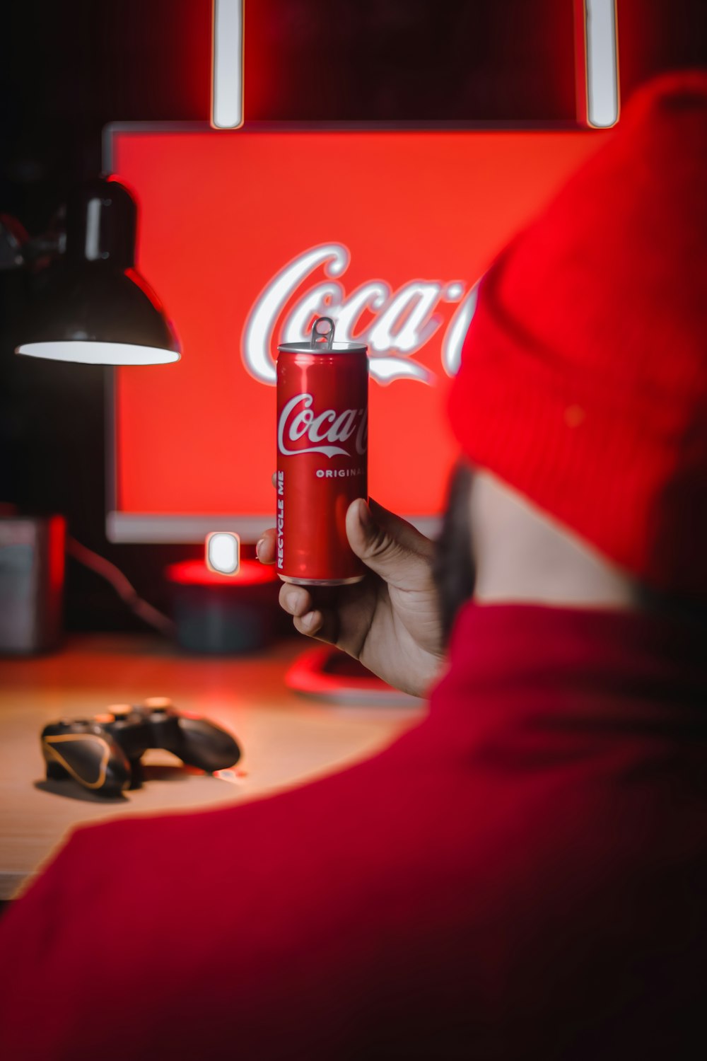 Ein Mann mit rotem Hut hält eine Dose Koka-Cola in der Hand