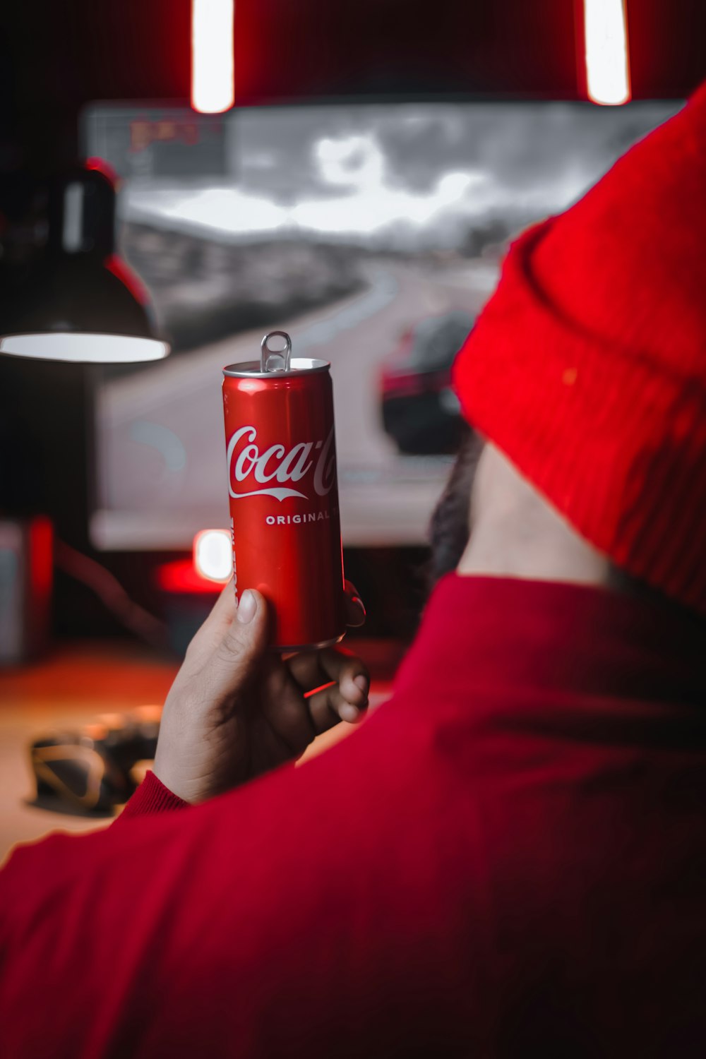 a man in a red hat holding a can of coca - cola