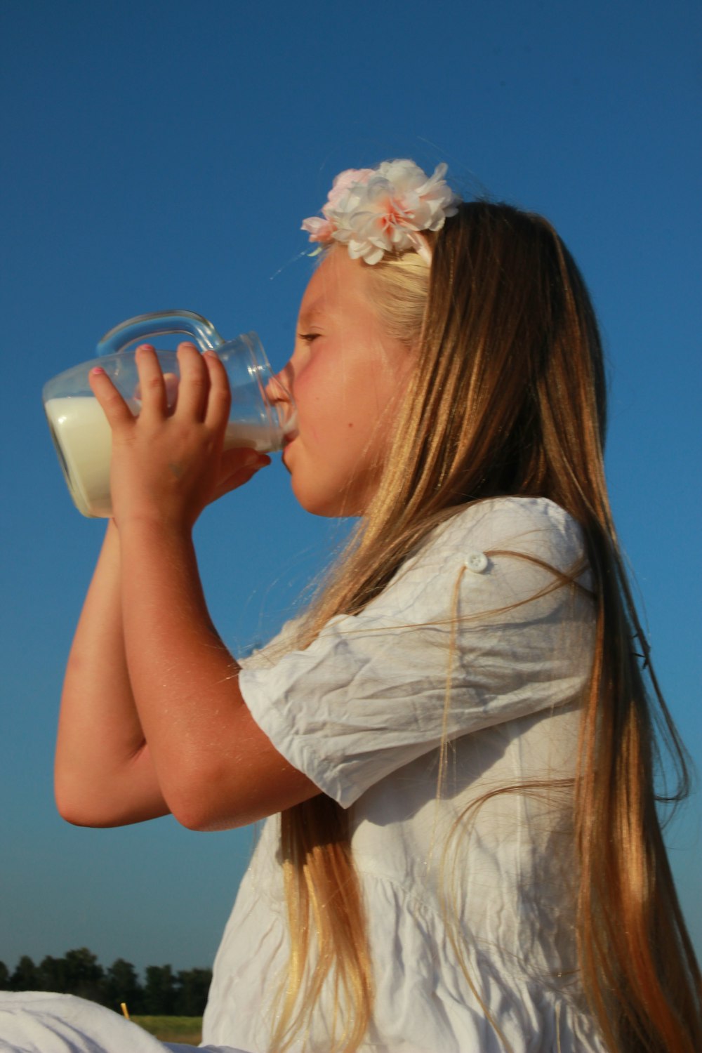 a young girl drinking from a bottle of milk