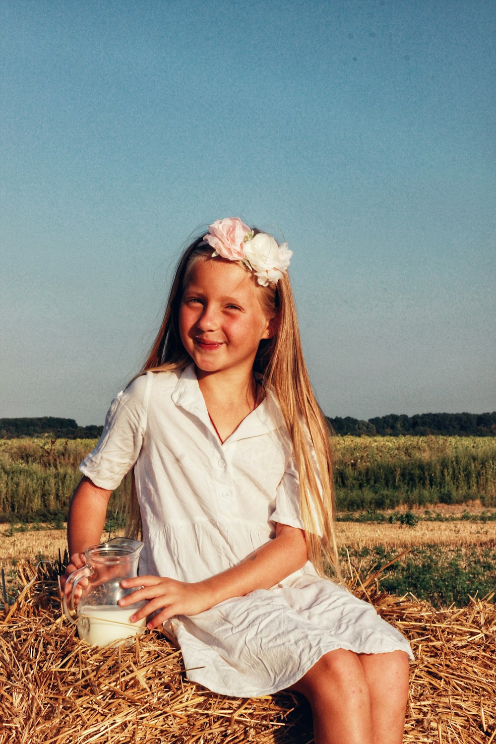 a little girl sitting on a pile of hay